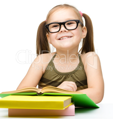 Cute cheerful little girl reading book