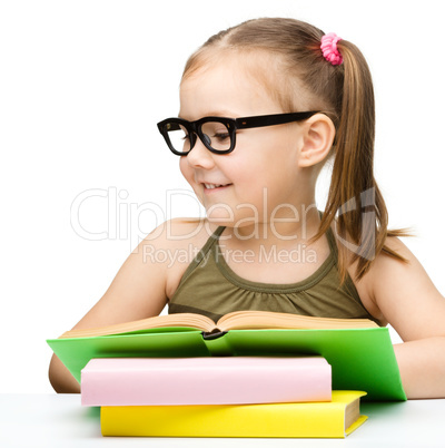 Cute cheerful little girl reading book