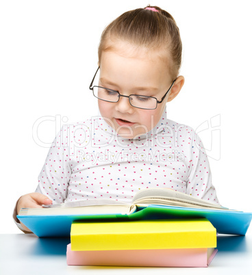 Cute little girl reading book wearing glasses