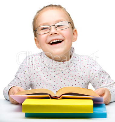 Cute cheerful little girl reading book