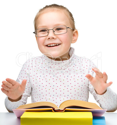 Cute cheerful little girl reading book