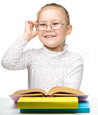 Cute cheerful little girl reading book