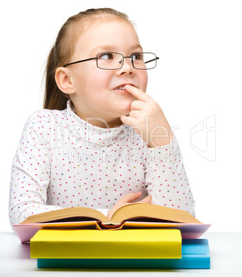 Cute little girl is dreaming while reading book