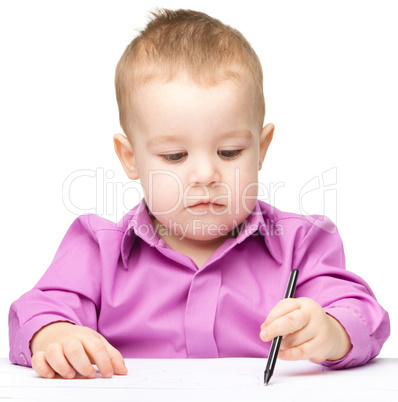 Cute little boy is drawing with pen