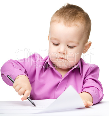 Cute little boy is drawing with pen