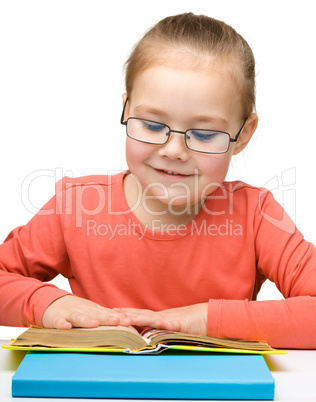 Cute cheerful little girl reading book