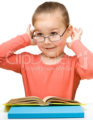 Cute cheerful little girl reading book