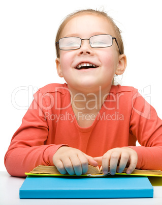 Cute cheerful little girl reading book