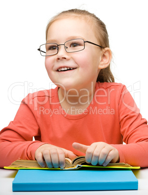 Cute cheerful little girl reading book