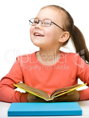 Cute cheerful little girl reading book