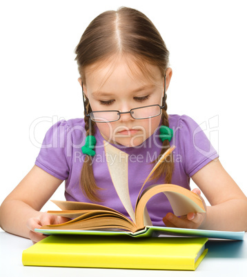 Cute cheerful little girl reading book