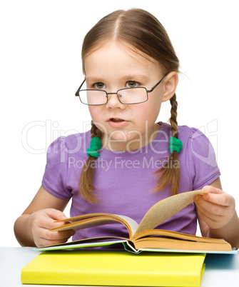 Cute little girl reading book wearing glasses
