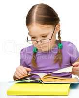 Cute little girl reading book wearing glasses