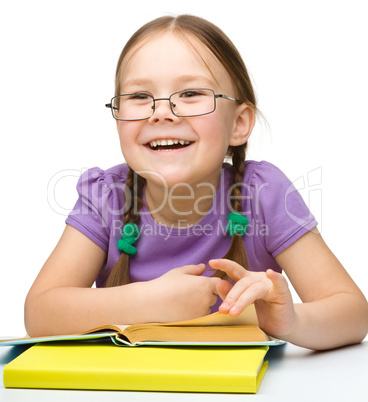 Cute cheerful little girl reading book