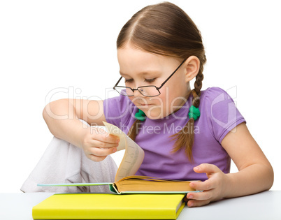 Cute little girl reading book wearing glasses