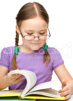 Cute little girl reading book wearing glasses