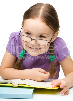 Cute cheerful little girl reading book