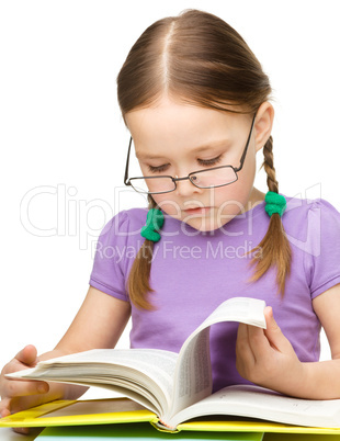 Cute little girl reading book wearing glasses
