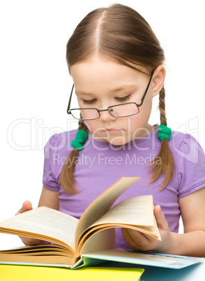 Cute little girl reading book wearing glasses