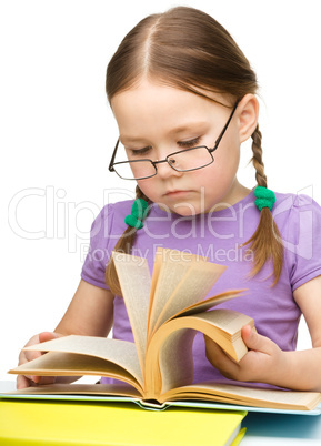 Cute little girl reading book wearing glasses