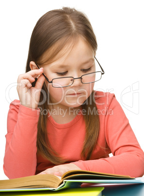 Cute little girl reading book wearing glasses