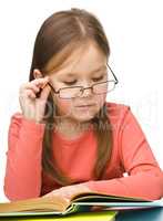 Cute little girl reading book wearing glasses