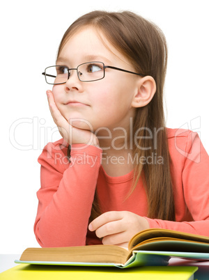 Cute little girl is dreaming while reading book