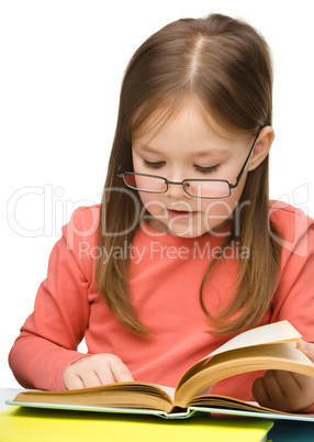 Cute little girl reading book wearing glasses