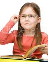 Cute little girl reading book wearing glasses