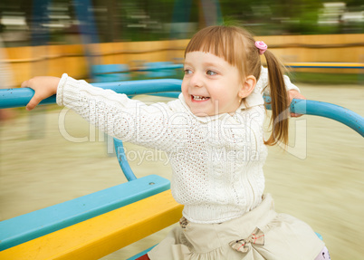 Cute little girl is riding merry-go-round