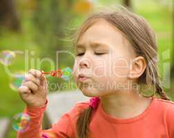 Cute little girl is blowing soap bubbles