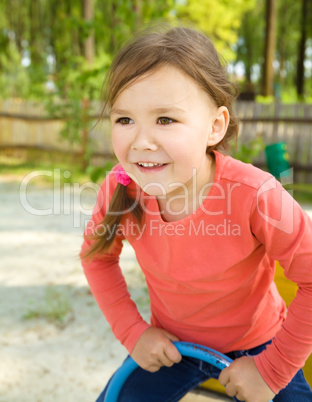 Happy little girl is swinging on see-saw