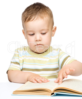 Cute little boy is reading book