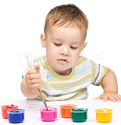 Little boy is playing with paints