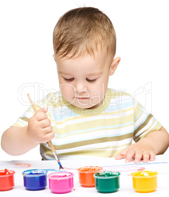 Little boy is playing with paints