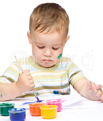 Little boy is playing with paints