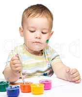 Little boy is playing with paints