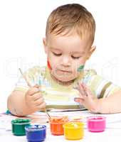 Little boy is playing with paints