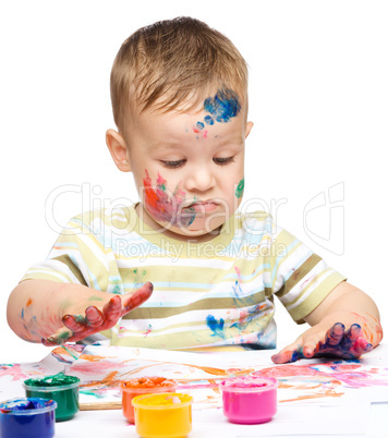 Little boy is playing with paints