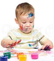 Little boy is playing with paints