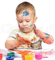 Little boy is playing with paints