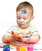 Little boy is playing with paints