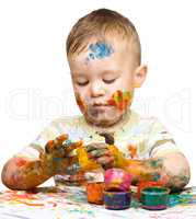 Little boy is playing with paints