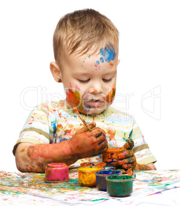 Little boy is playing with paints