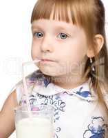 Cute little girl drinks milk using drinking straw