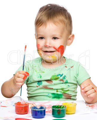 Little boy is playing with paints