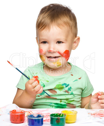 Little boy is playing with paints