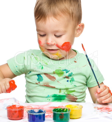 Little boy is playing with paints