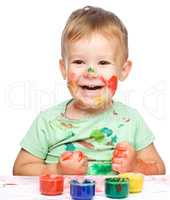 Little boy is playing with paints