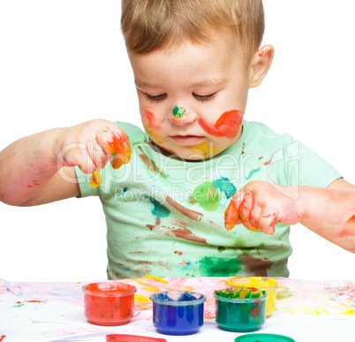 Little boy is playing with paints